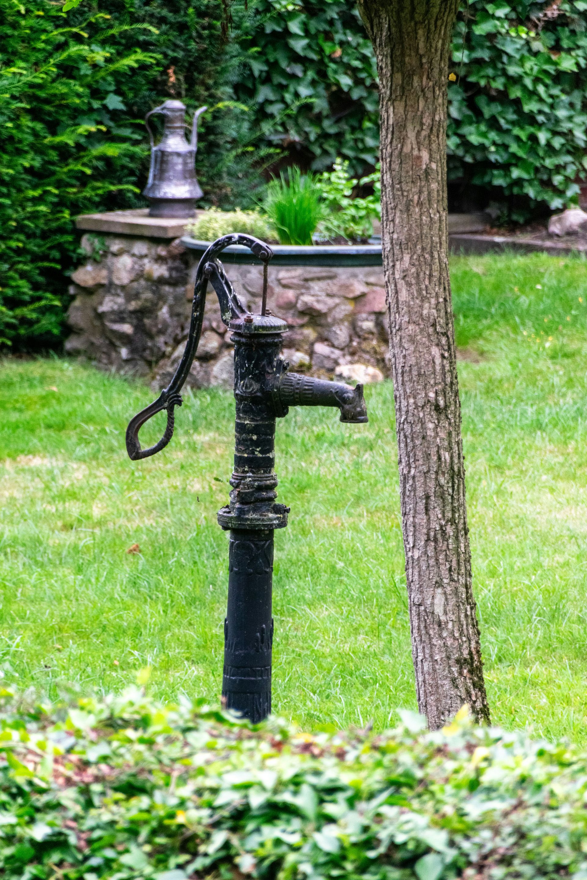 An old water pump stands in a grassy garden