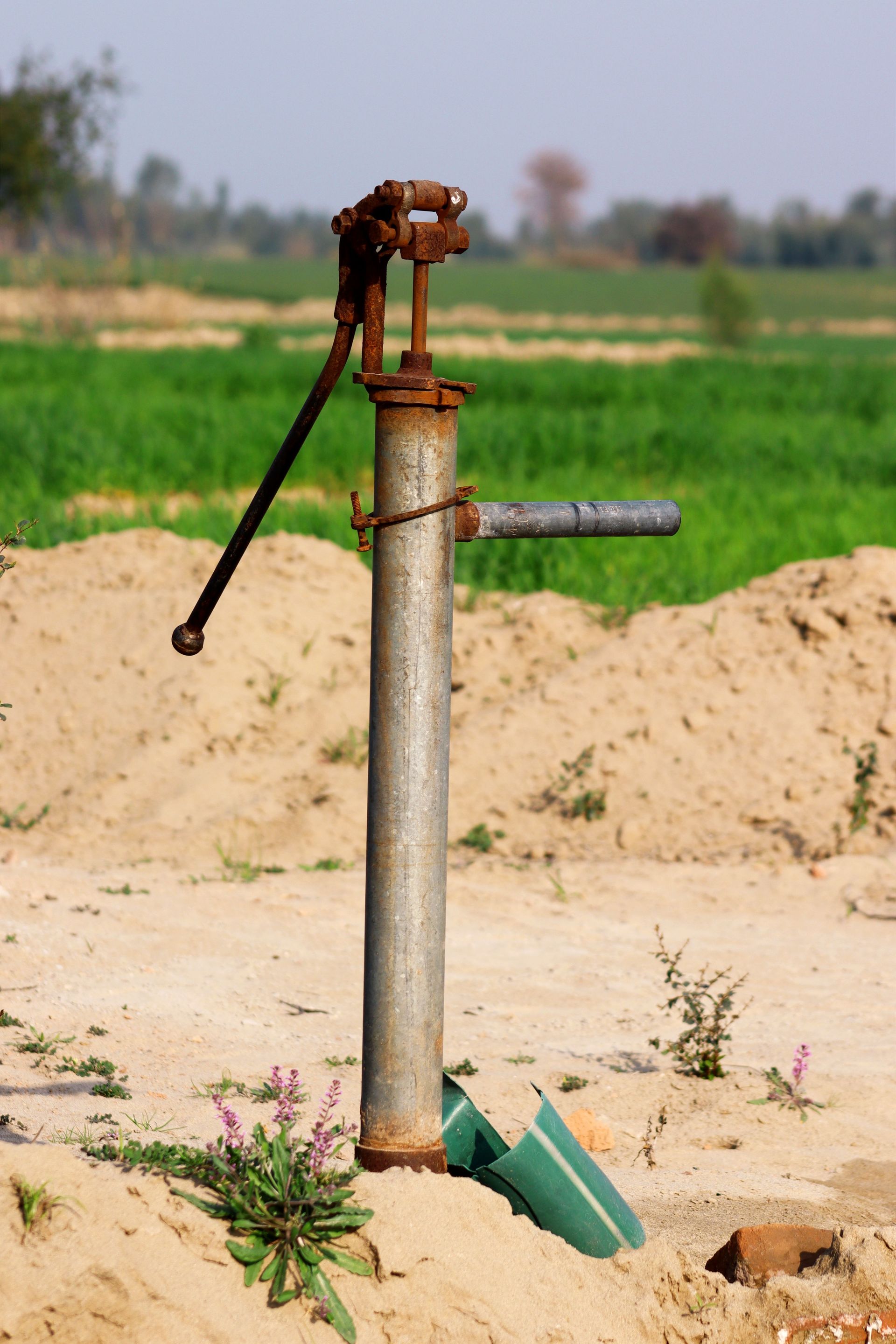 Rustic water pump in a rural Pakistani field during daytime.